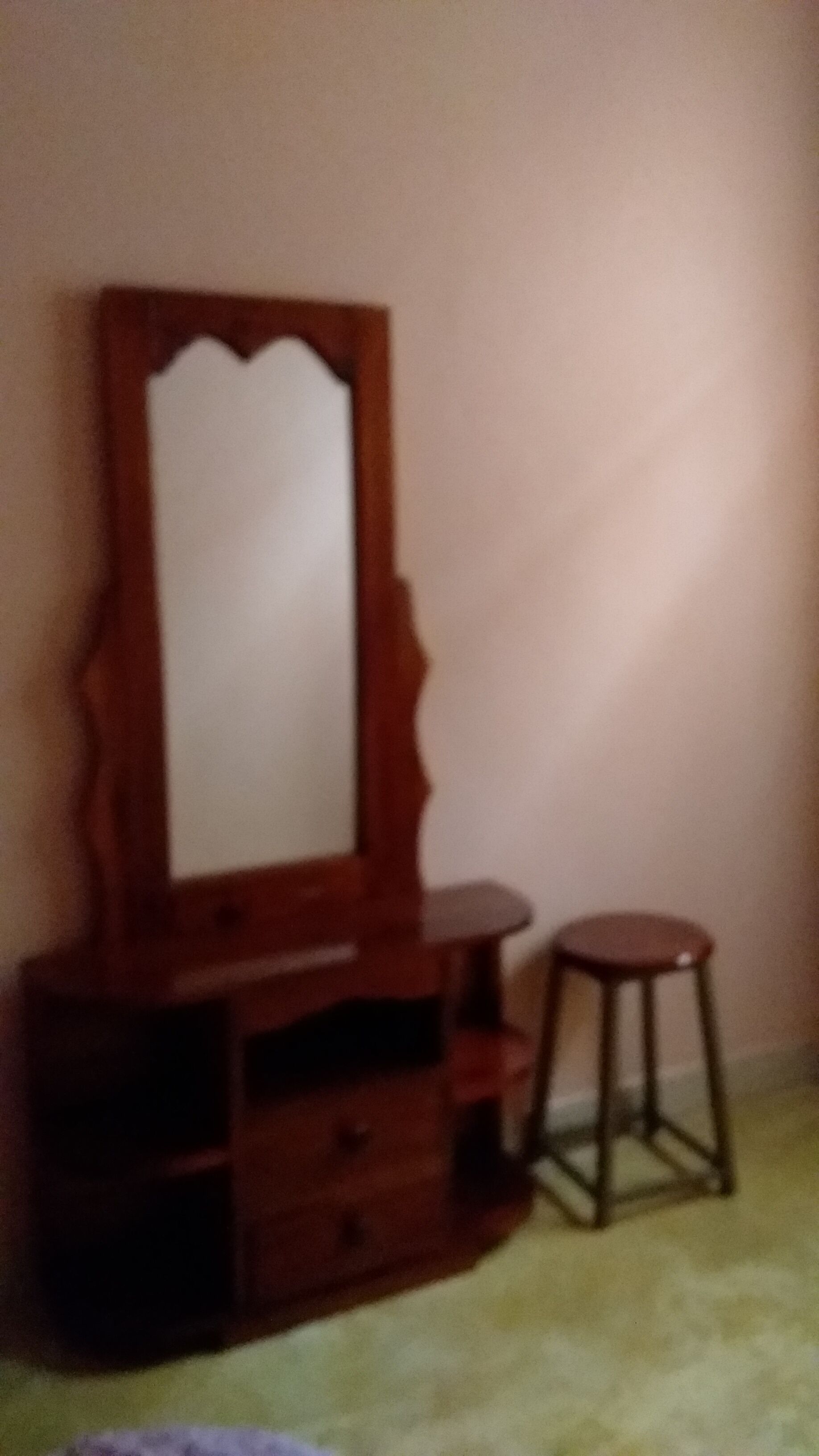 A wooden dresser with a mirror and a stool.