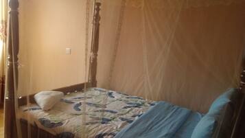 Una cama individual con dosel, una mesita de noche y un enchufe de pared.