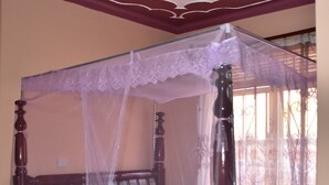 A four-poster canopy bed with a lace canopy, wooden headboard, and a floral bedspread.