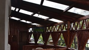 A rustic wooden interior with a high ceiling and skylights, stone flooring, and wooden furniture.