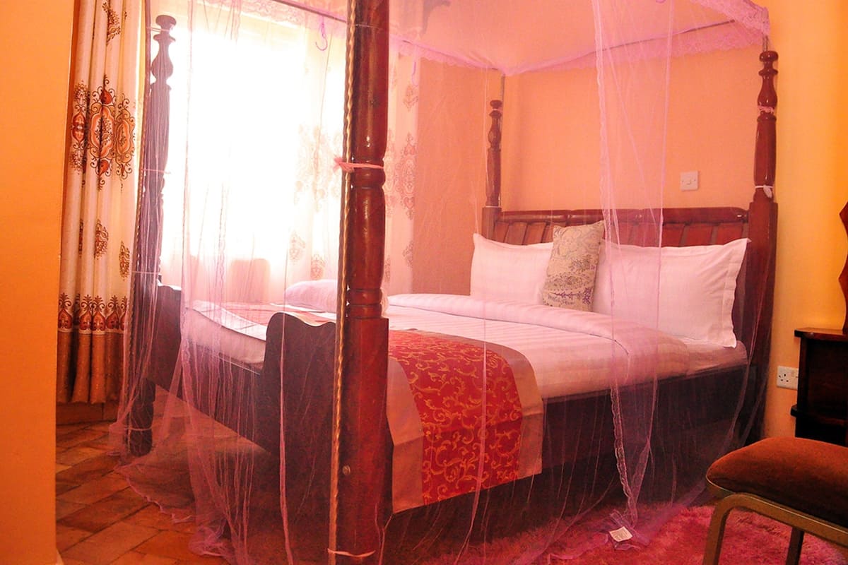 A four-poster bed with a canopy, a wooden headboard, and a red bedspread.