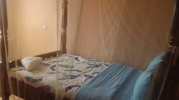 A single bed with a canopy, a pillow, and a blanket.
