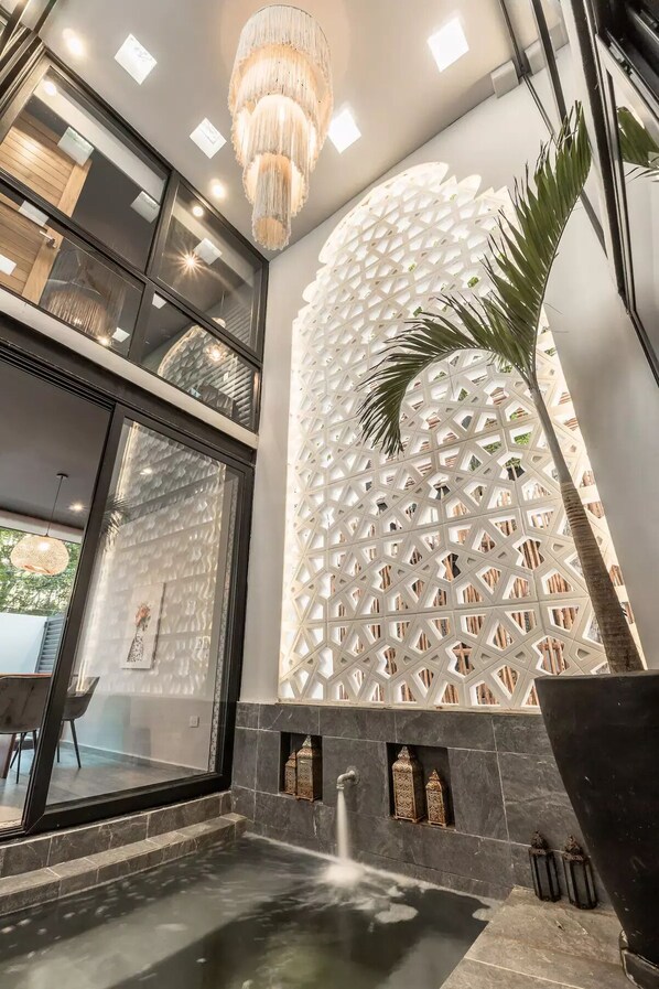Ein modernes Interieur mit geometrischem Wanddesign, einer Wasserspielen und einem Kronleuchter.