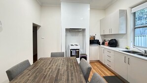 Een kleine keuken met een eettafel, stoelen, een fornuis en kastjes.