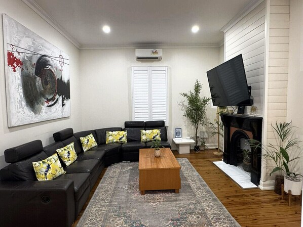 A living room with a sectional sofa, a coffee table, a fireplace, and a large painting.
