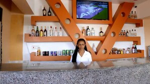 Zona de bar con estanterías llenas de botellas de licores y una pantalla de televisión mostrando un evento deportivo.