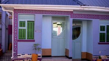 A building with a reception area, a door, and a window with green shutters.
