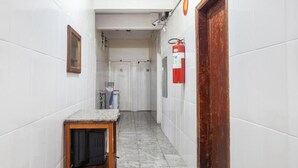 Un passadís estret amb parets de rajoles blanques, una taula de fusta i un televisor, i un extintor col·locat a la paret.