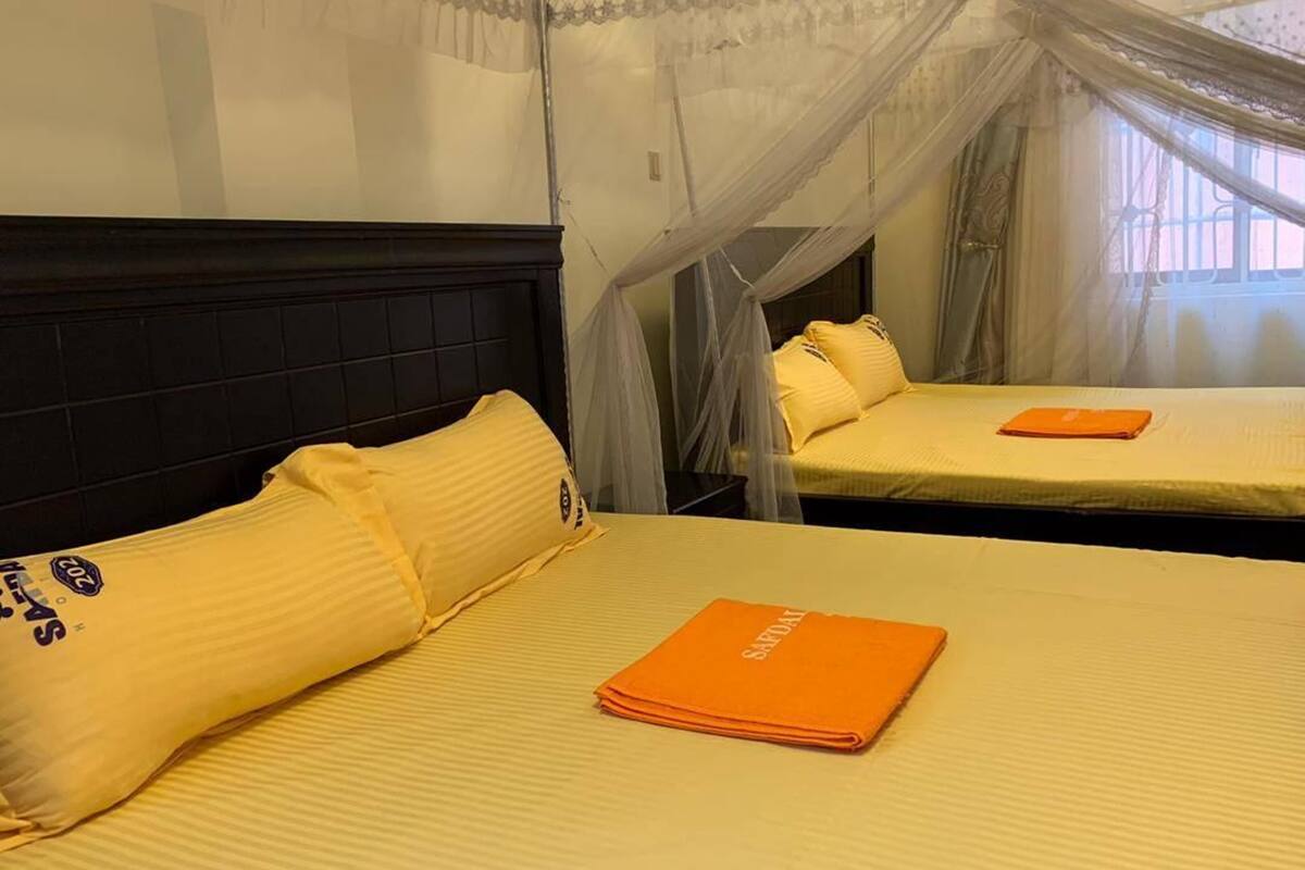 Habitación de hotel con dos camas, una cama con dosel y una ventana con cortinas.