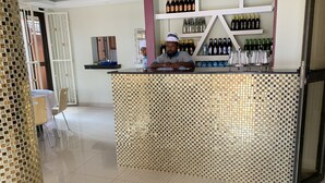Eine Bar mit einer gemusterten Theke, Regalen voller verschiedener Flaschen und einem Stuhl.