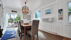Un coin repas avec une table en bois, des chaises à motifs, un tapis bleu et un luminaire suspendu au plafond.