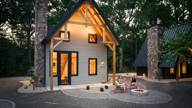 Un chalet rustique avec une façade en pierre, une terrasse en bois et un foyer extérieur.