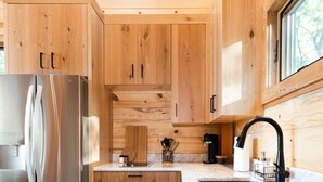 Une cuisine moderne avec des meubles en bois, un réfrigérateur en acier inoxydable, un évier et une fenêtre au-dessus du plan de travail.