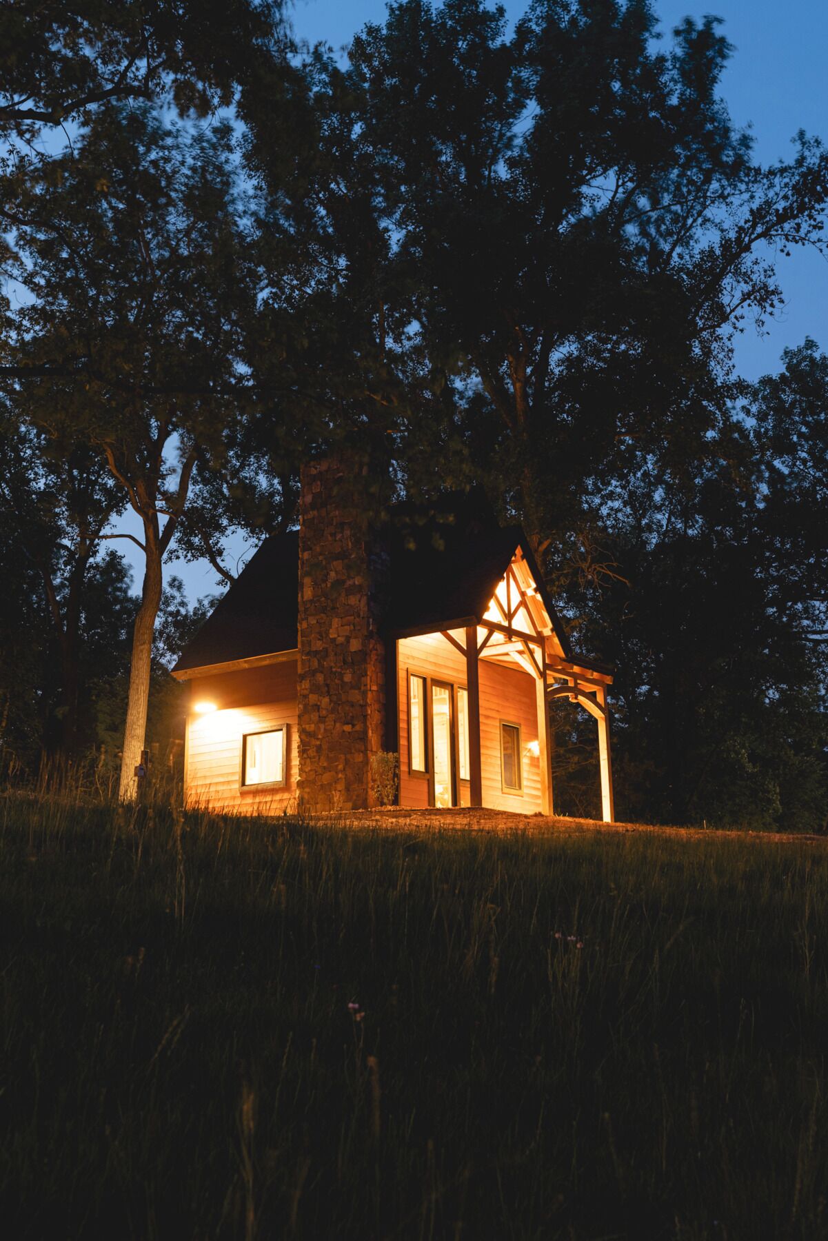 Un chalet rustique avec une cheminée en pierre, des murs en bois et une véranda.