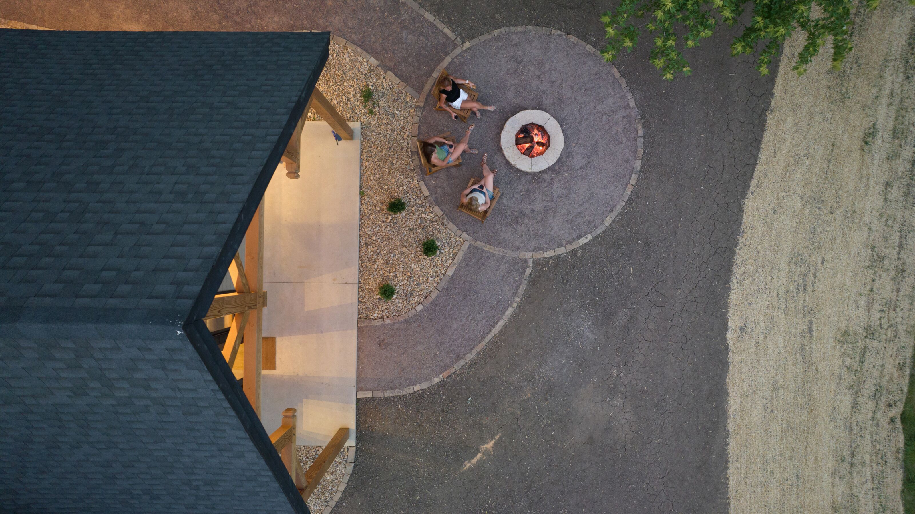 An aerial view of a courtyard with a fire pit, seating area, and a building with a sloped roof.