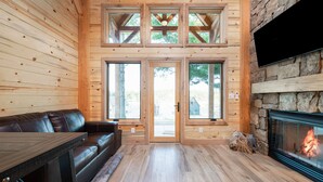 A log cabin interior with a fireplace, wooden walls, a leather couch, and a dining table. - #8 Cottonwood Corner (Dahinda)