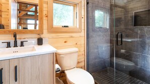 A modern bathroom with wooden paneling, a glass shower enclosure, and a large mirror. - #8 Cottonwood Corner (Dahinda)