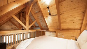 A wooden interior with a bed, wooden beams, and a railing. - #8 Cottonwood Corner (Dahinda)