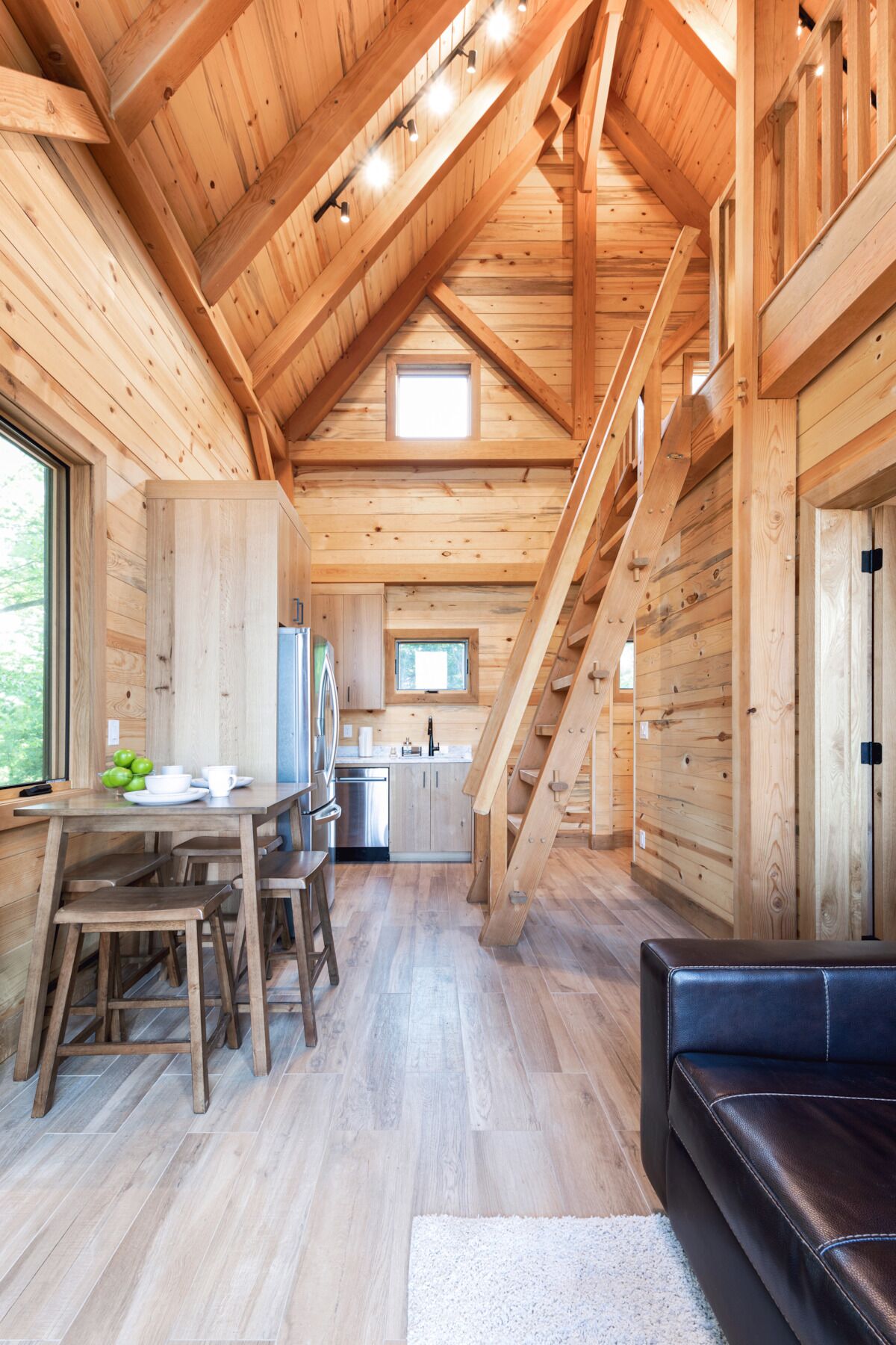 Ein Holzblockhaus-Interieur mit Essbereich, Küche und einer Treppe, die zu einer oberen Ebene führt.