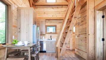 Ein Holzblockhaus-Interieur mit Essbereich, Küche und einer Treppe, die zu einer oberen Ebene führt.