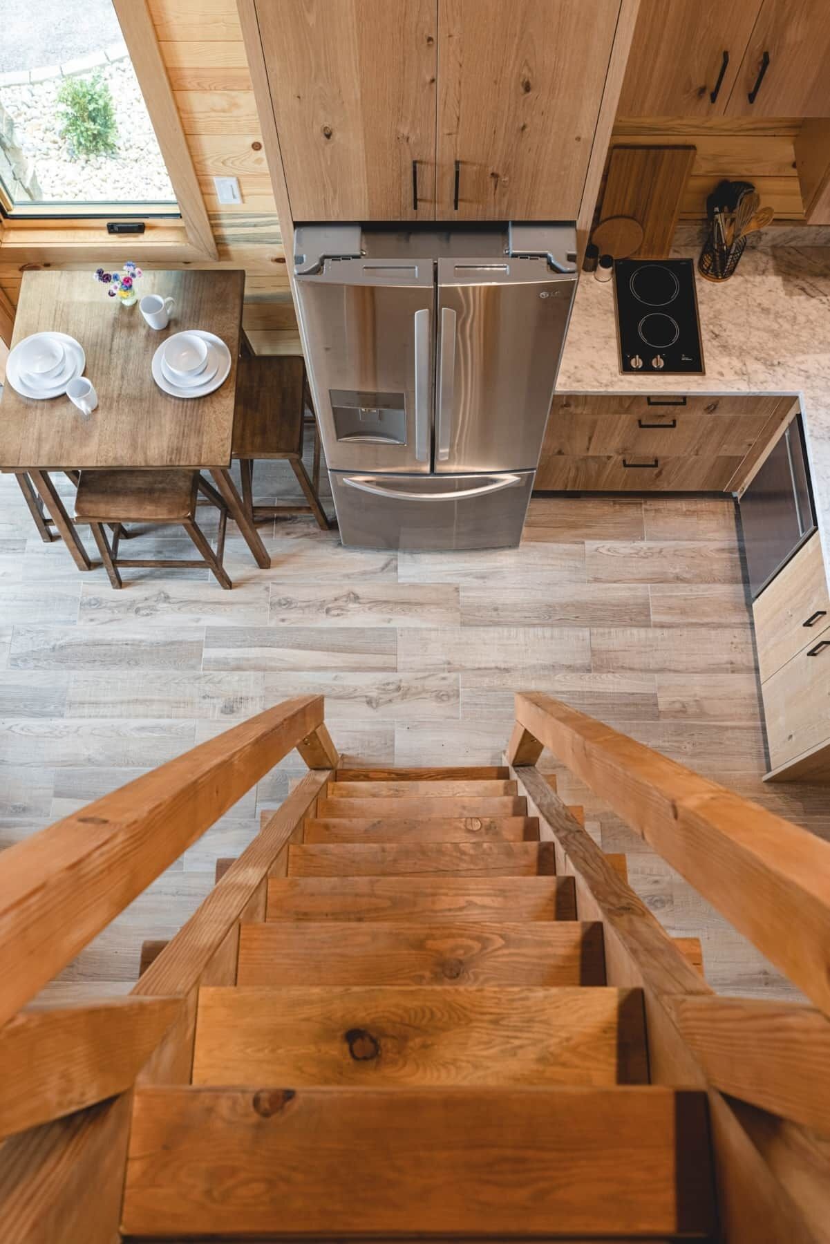 Eine moderne Küche mit Holzschränken, einem Edelstahlkühlschrank und einem Essbereich mit Tisch für zwei Personen.