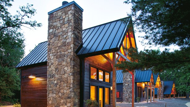 A modern building with a stone chimney, large windows, and a metal roof. - #20 Bluegill Cove (Dahinda)