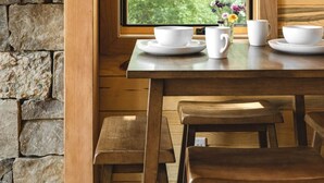 A wooden table with white dishes and a vase of flowers by a window with a stone wall backdrop. - #20 Bluegill Cove (Dahinda)