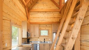 A wooden cabin interior with a kitchen, dining area, and a staircase. - #20 Bluegill Cove (Dahinda)