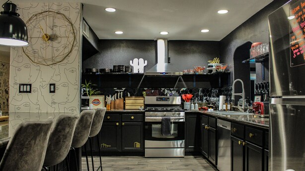 Una cocina moderna con electrodomésticos de acero inoxidable, asientos de bar y un menú en una pizarra.