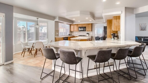 A spacious kitchen with a large island, bar stools, and modern appliances. - Bright&Open, Lrg home @DIA w/Pool Table & Firepit (Denver)