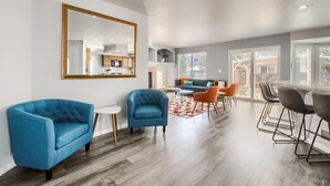 A modern living room with a sofa, chairs, a coffee table, and a dining area with bar stools. - Bright&Open, Lrg home @DIA w/Pool Table & Firepit (Denver)