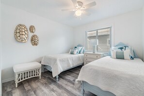 A bedroom with two beds, a nightstand, a bench, and a ceiling fan. - Beachfront Condo Steps to Beach! Incredible View of the Gulf of Mexico! (Indian Shores)