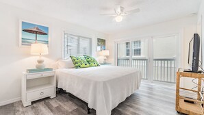 A bedroom with a bed, nightstands, a ceiling fan, and a TV on a stand.