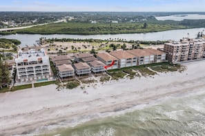 A beachfront hotel with multiple buildings, a sandy beach, and a river in the background.