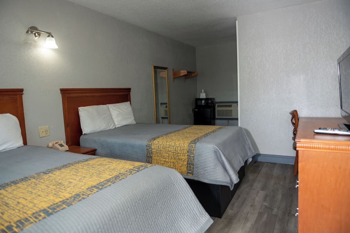 A hotel room with two beds, a desk, a mirror, a telephone, and a coffee machine.