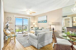 Relax in a spacious living area with a sofa, chairs, dining table, and coffee table, offering a view of the outdoors.