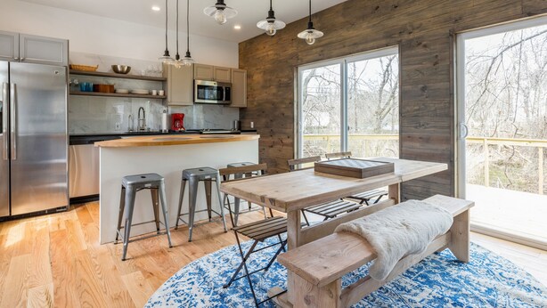 Eine moderne Küche mit einer Holz-Akzentwand, Edelstahlgeräten und einem großen Fenster mit Blick auf eine Terrasse.