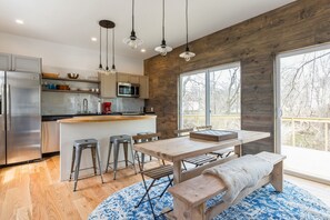 Una cocina moderna con una pared de acento de madera, electrodomésticos de acero inoxidable y un ventanal con vistas a una terraza.