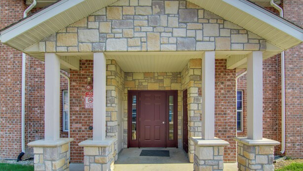 A stone building with a red door and a covered entrance.