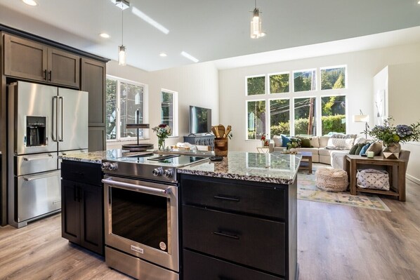 A modern kitchen with a large island, built-in appliances, and a dining area with a sofa and table.