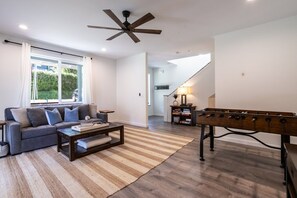 Een moderne woonkamer met een bank, salontafel en een tafelvoetbal.