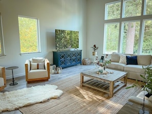 A spacious living room with a sofa, armchair, coffee table, and a large window.