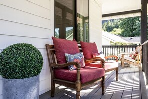 A wooden porch with a bench and a potted plant.