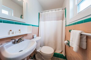 Une salle de bain avec un lavabo blanc, des toilettes et un rideau de douche.