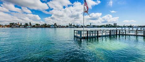 A waterfront view with a dock and a flagpole.