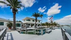 A waterfront property with a dock, palm trees, and a flag.