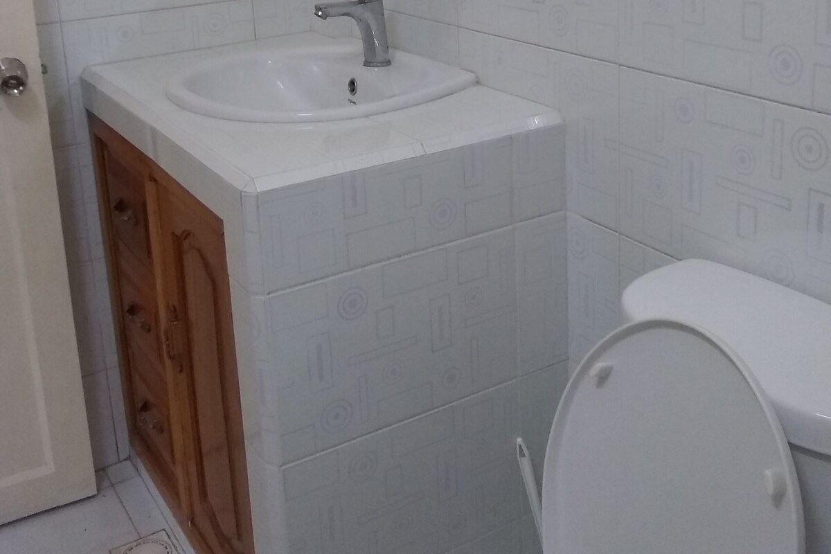 A bathroom with a white sink, a mirror above it, and a toilet.