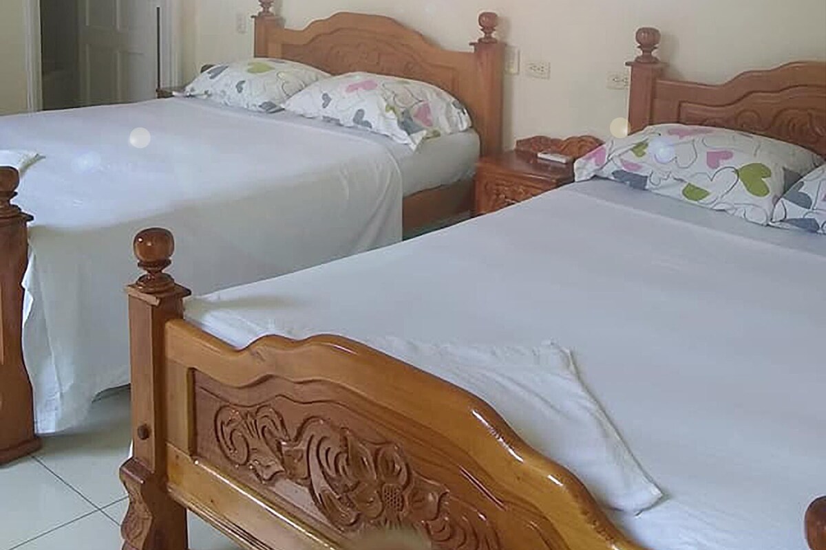 Two single beds with wooden headboards in a room with a door and a light fixture on the wall.