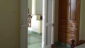 Ein Zimmer mit einem Bett, einem Holzschrank und einer Tür zu einem anderen Raum.