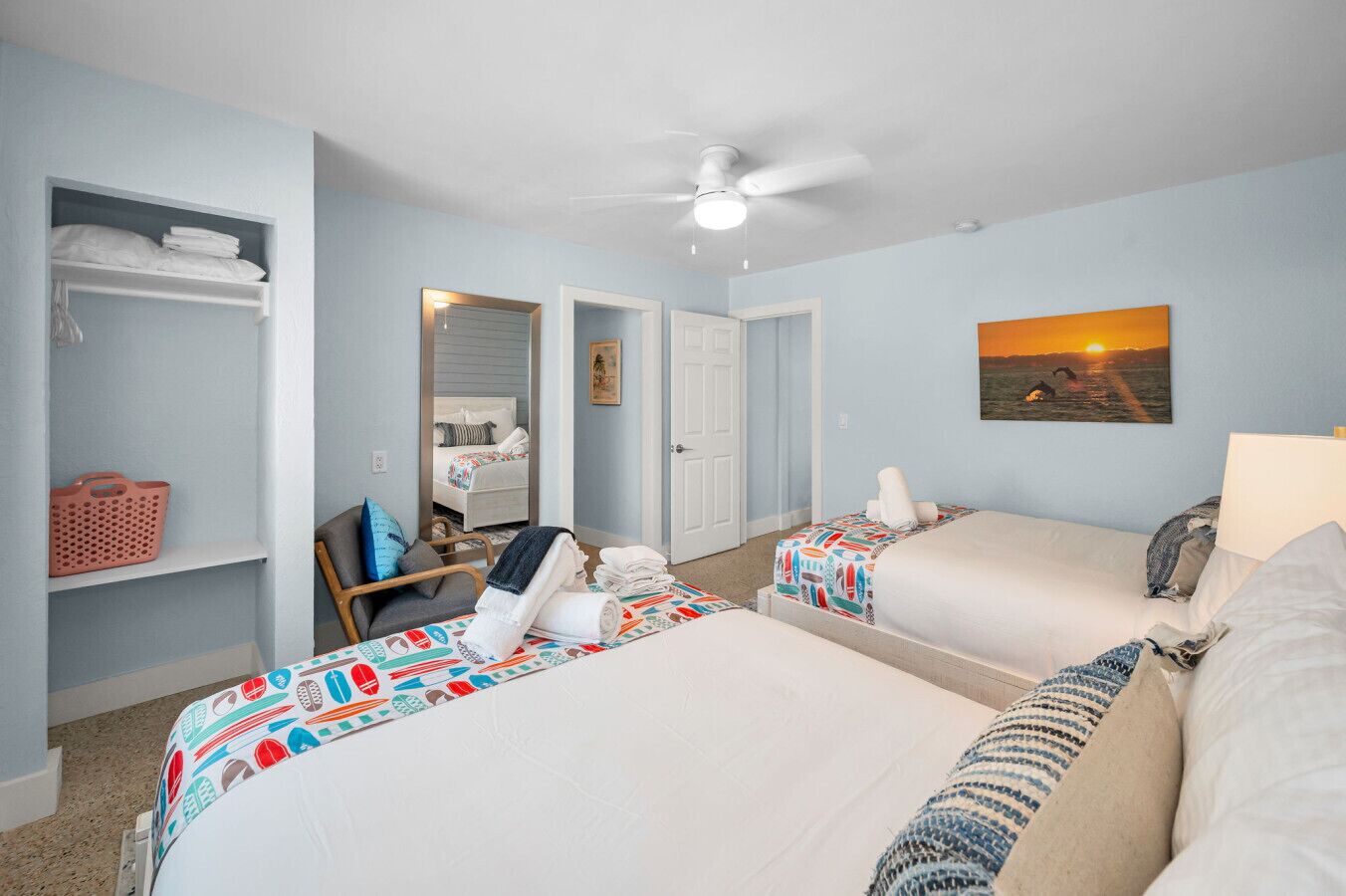 A bedroom with two beds, a chair, a wardrobe, and a ceiling fan.
